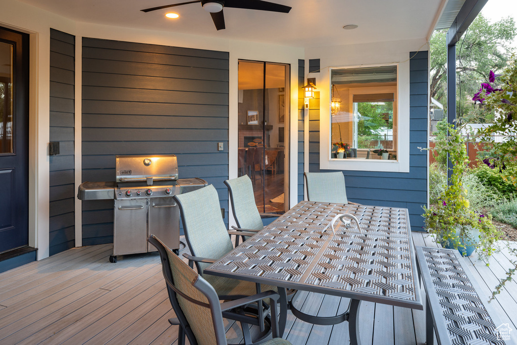 Wooden terrace featuring outdoor dining area, area for grilling, and ceiling fan