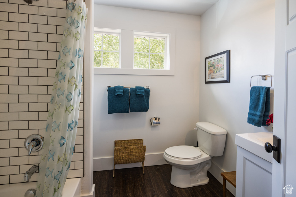 Full bath featuring vanity, toilet, shower / bath combination with curtain, baseboards, and wood finished floors