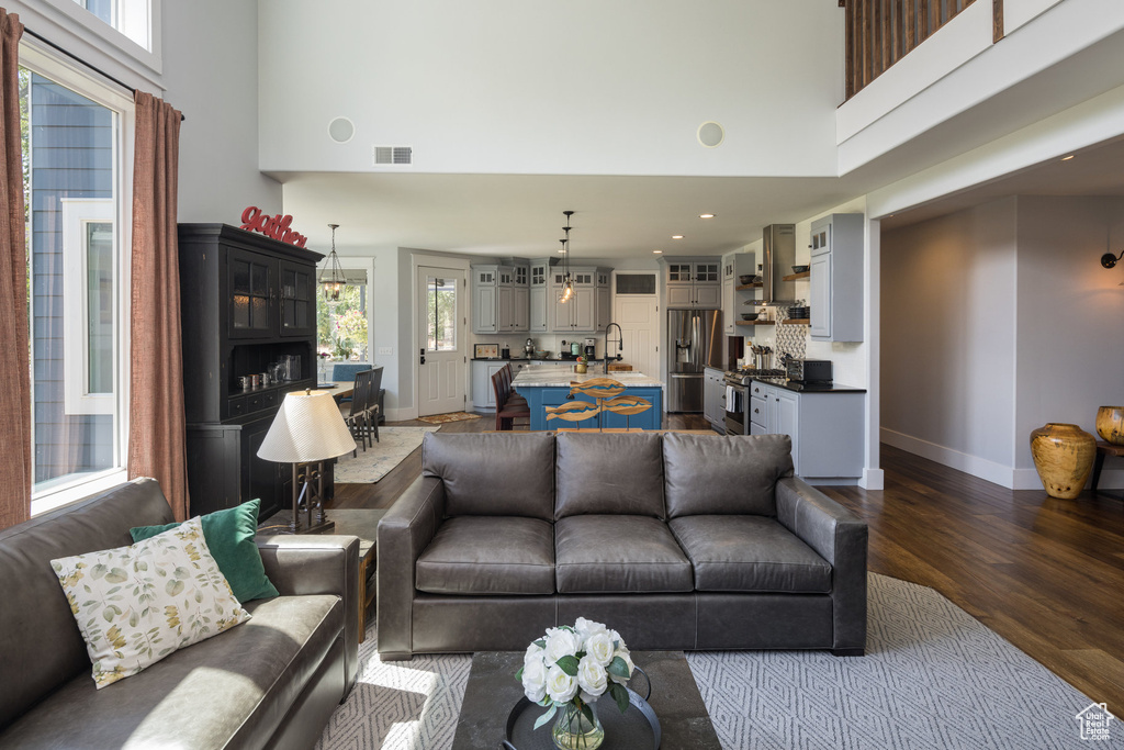 Living area with visible vents, baseboards, dark wood-style floors, a high ceiling, and recessed lighting