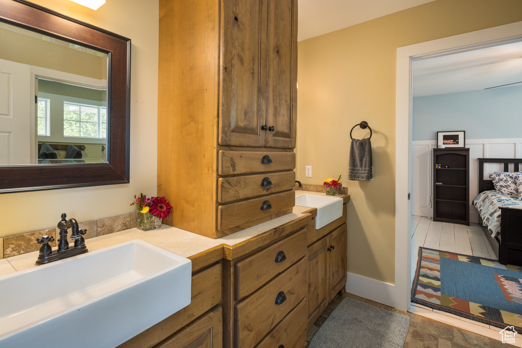 Full bath with connected bathroom, double vanity, and a sink