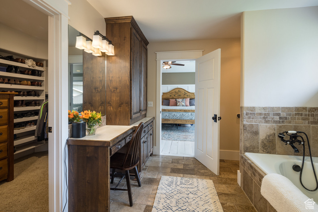 Bathroom with ceiling fan, a garden tub, ensuite bath, and stone tile flooring