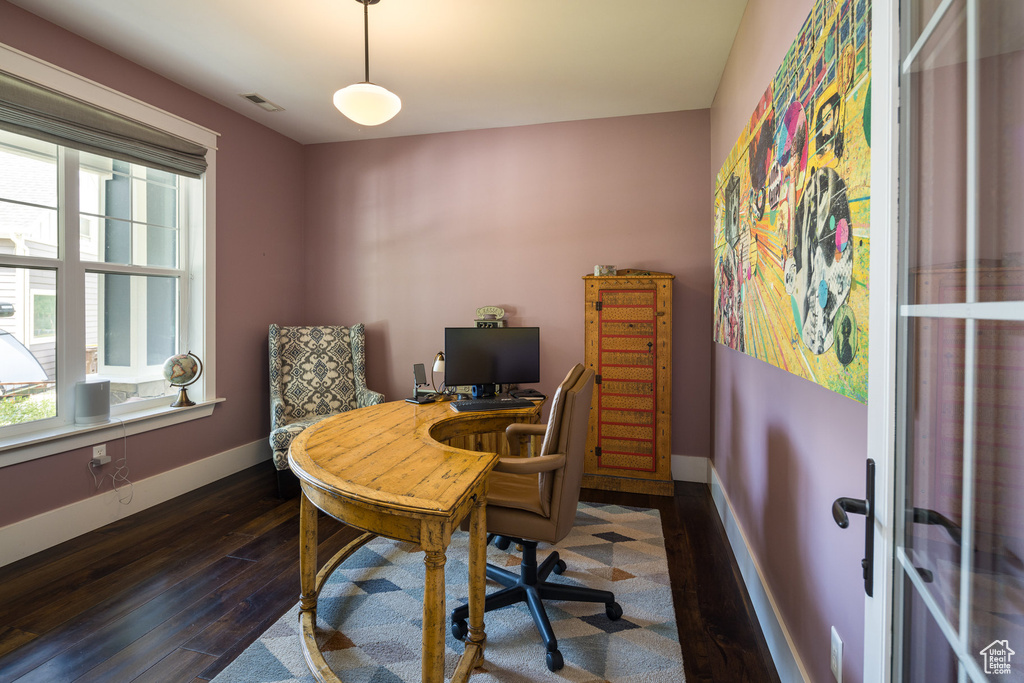 Home office with visible vents, baseboards, a wealth of natural light, and dark wood-style floors