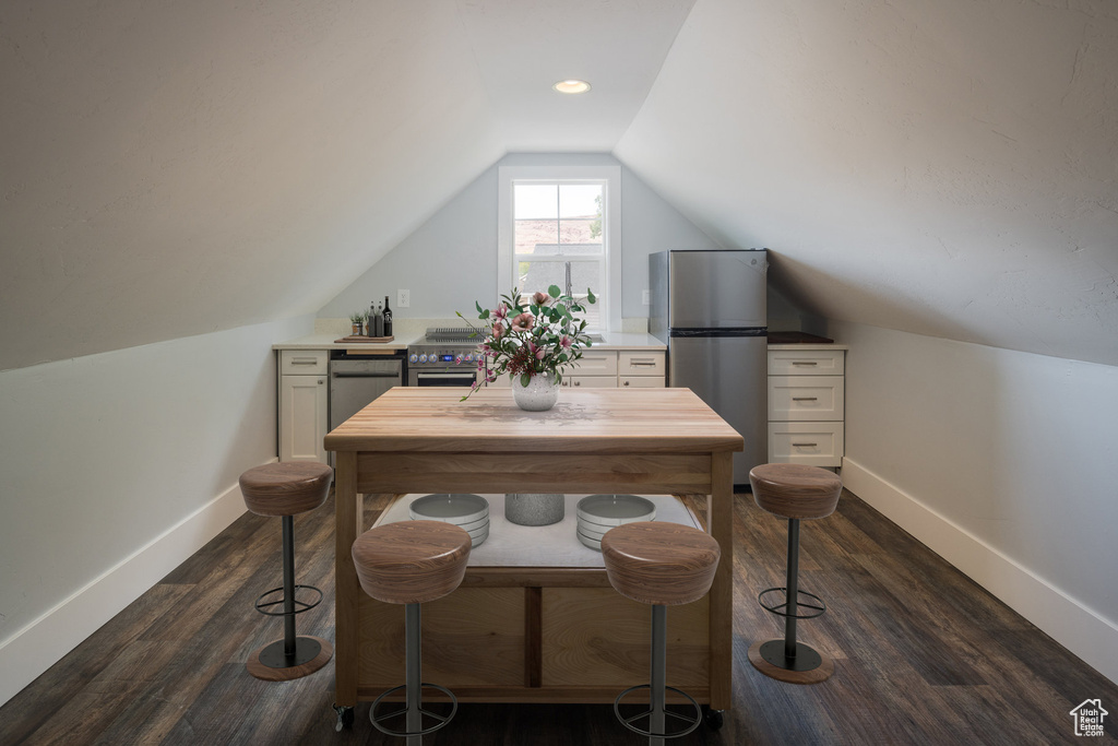 Interior space featuring dark wood-style flooring, baseboards, and lofted ceiling
