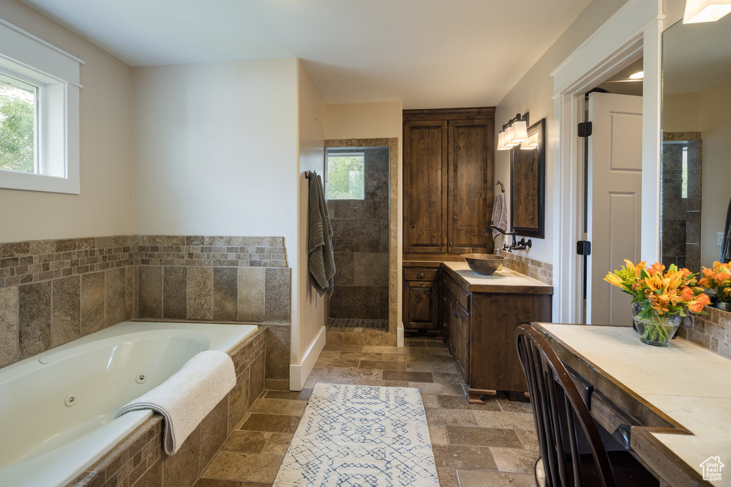 Full bath with stone tile flooring, walk in shower, and a wealth of natural light