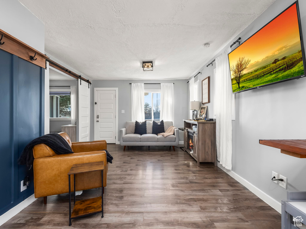 Living room featuring a barn door, dark hardwood / wood-style flooring, and a textured ceiling