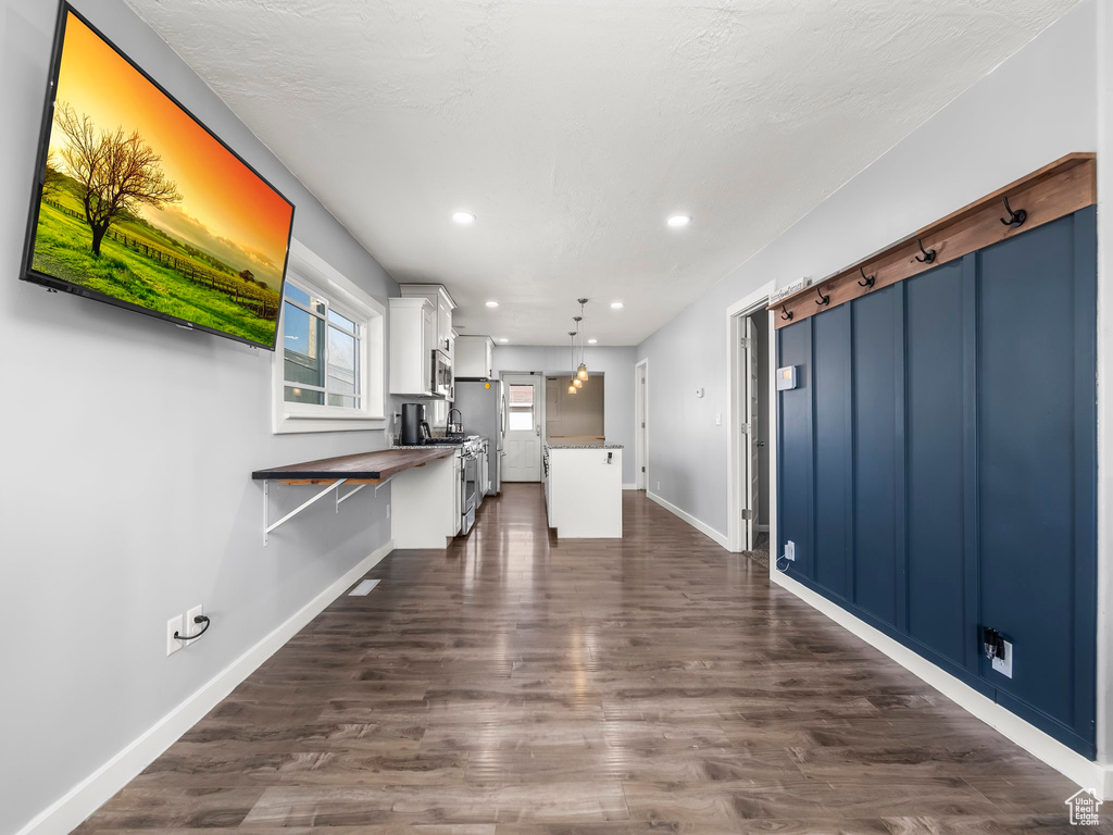 Kitchen with decorative light fixtures, white cabinets, stainless steel appliances, a barn door, and dark wood-type flooring