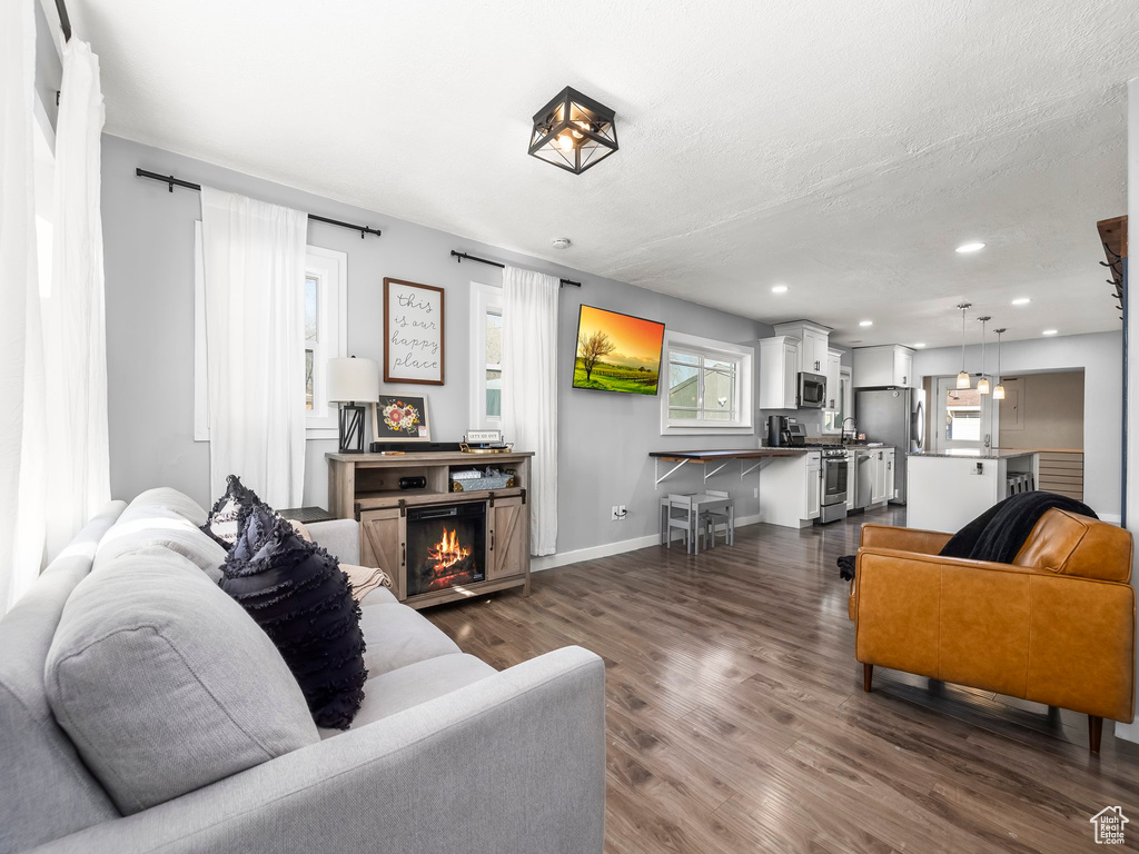 Living room featuring dark wood-type flooring, a textured ceiling, and a fireplace