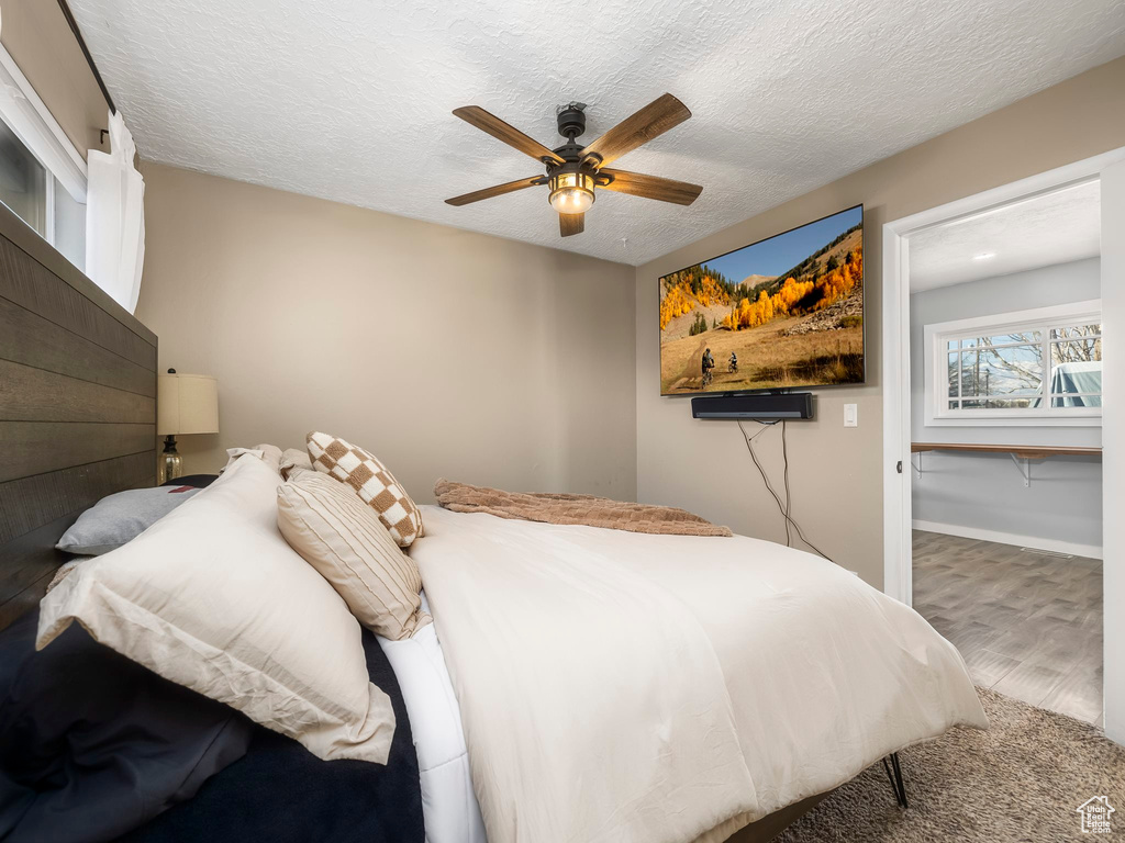 Bedroom featuring hardwood / wood-style flooring, ceiling fan, and a textured ceiling