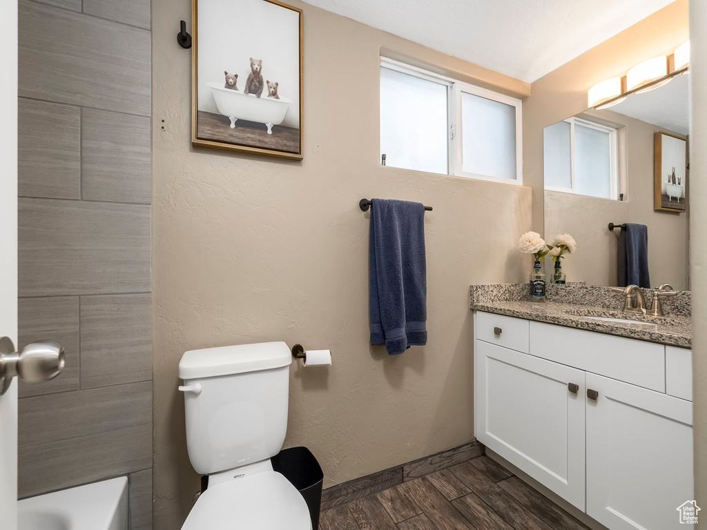 Bathroom with vanity, a tub to relax in, and toilet