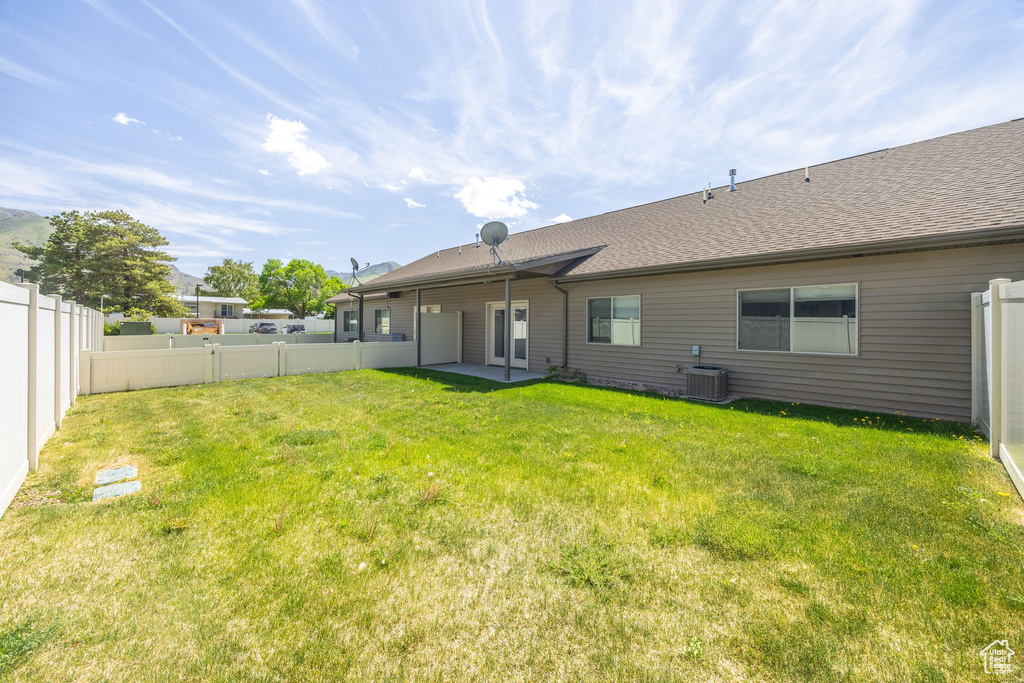 Rear view of property with central AC unit, a patio area, and roof with shingles