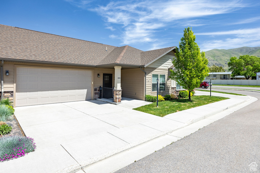 View of front of property with a mountain view, a garage, concrete driveway, and roof with shingles