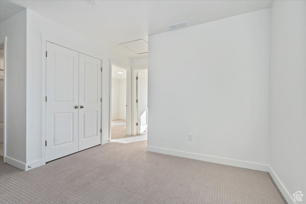 Unfurnished bedroom with light carpet and a closet