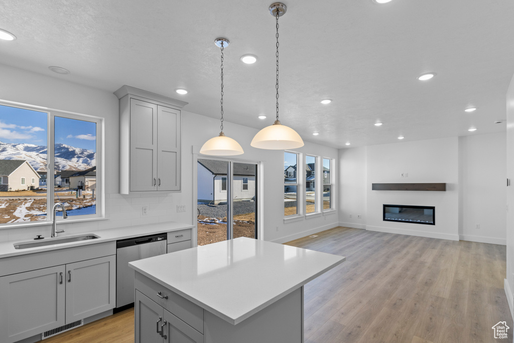 Kitchen with sink, gray cabinetry, hanging light fixtures, dishwasher, and backsplash