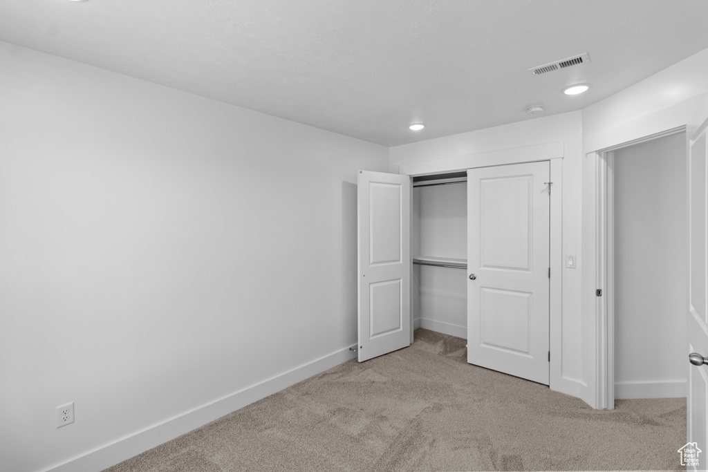 Unfurnished bedroom with light colored carpet and a closet