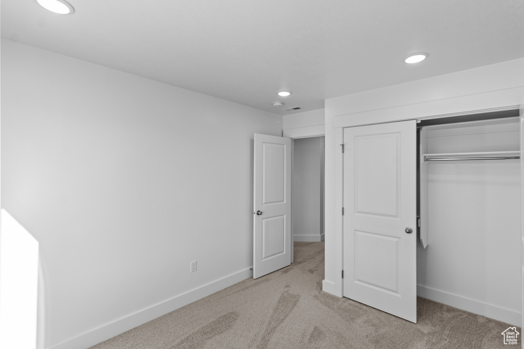 Unfurnished bedroom featuring light colored carpet and a closet