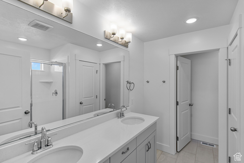 Bathroom featuring an enclosed shower, vanity, tile patterned flooring, and a textured ceiling