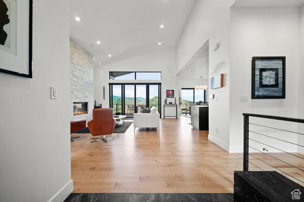 Interior space featuring a stone fireplace, light hardwood / wood-style flooring, and high vaulted ceiling