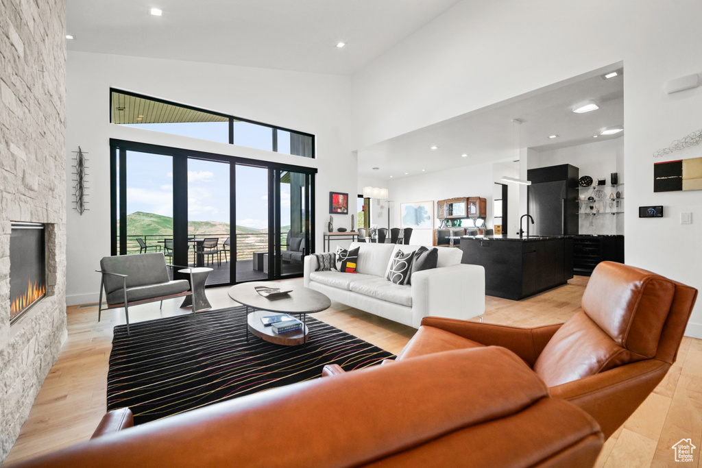 Living room featuring a towering ceiling, sink, a fireplace, and light hardwood / wood-style floors