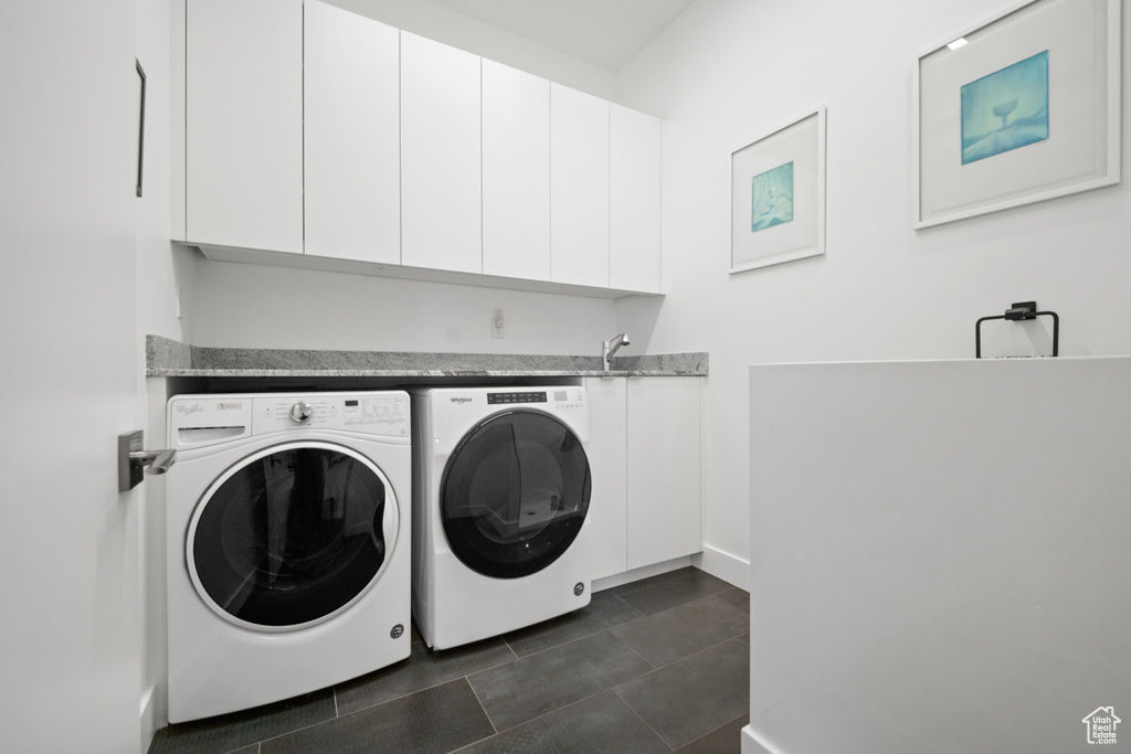 Washroom featuring cabinets, sink, and washing machine and clothes dryer