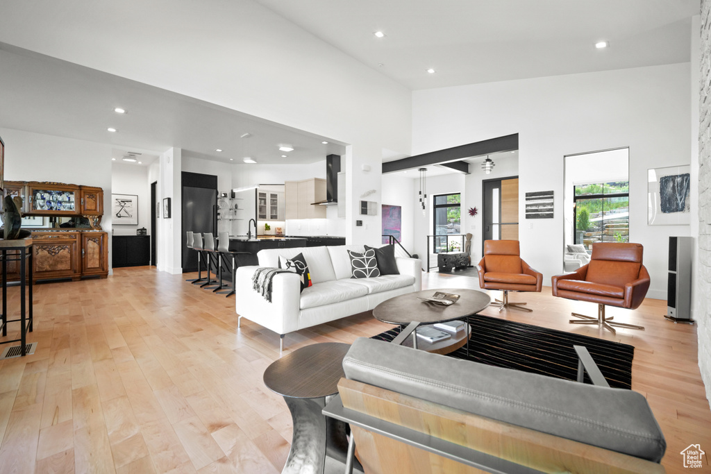 Living room featuring sink, high vaulted ceiling, and light wood-type flooring