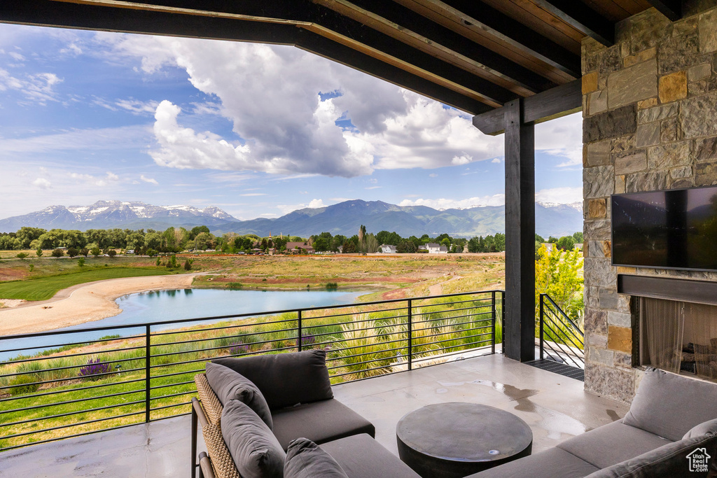 View of patio with an outdoor stone fireplace and a balcony
