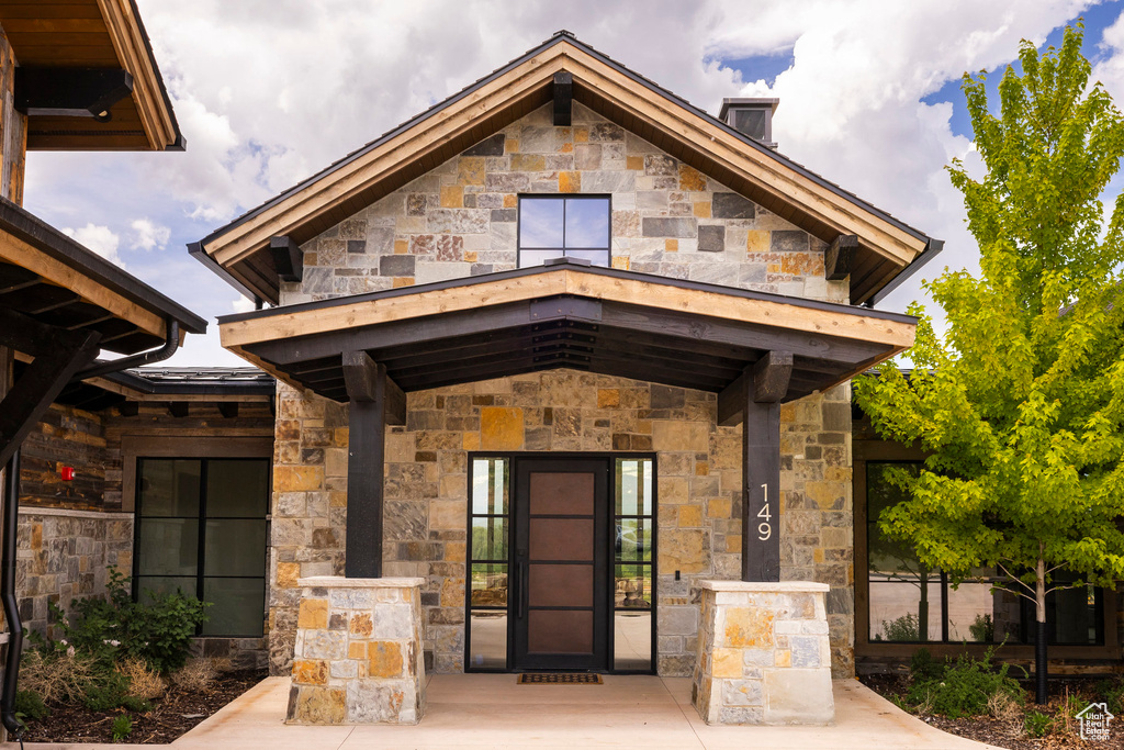 Doorway to property with stone siding, a balcony, and a chimney