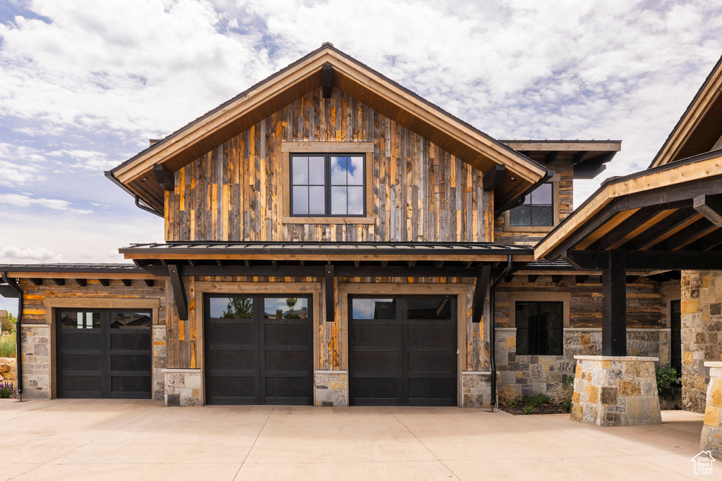 View of front of house with concrete driveway, an attached garage, stone siding, and board and batten siding