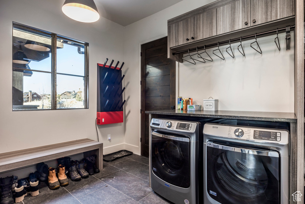 Laundry room with separate washer and dryer, dark tile patterned flooring, and baseboards