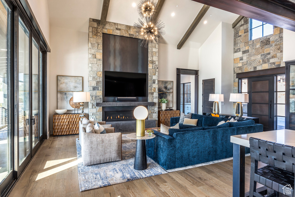 Living room with high vaulted ceiling, beam ceiling, wood finished floors, a glass covered fireplace, and radiator