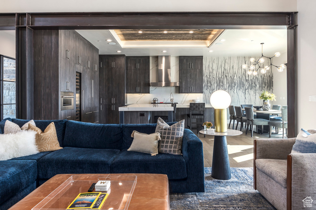 Living area featuring a chandelier, dark wood-style floors, a tray ceiling, and recessed lighting