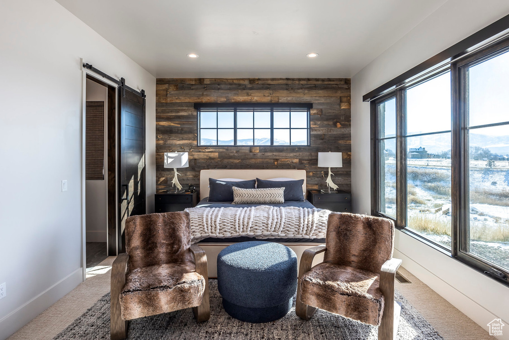 Carpeted bedroom with wooden walls, a barn door, an accent wall, recessed lighting, and baseboards