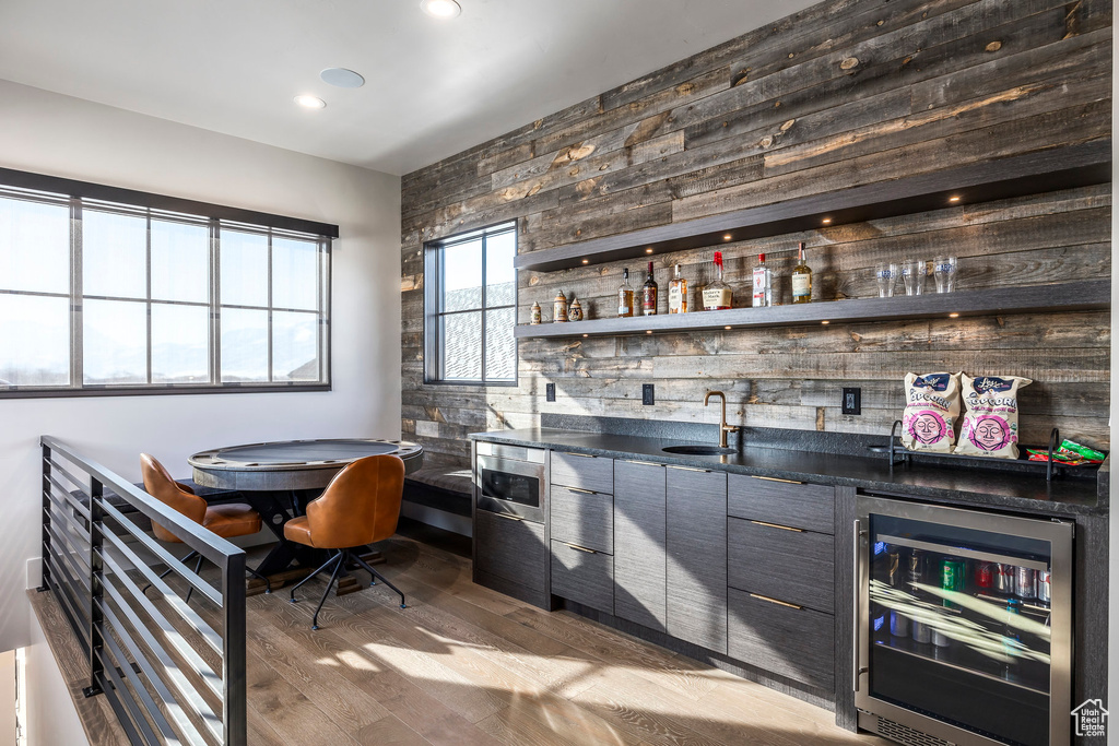 Indoor wet bar featuring beverage cooler, wood finished floors, recessed lighting, and wood walls