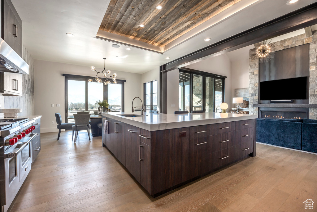 Kitchen with modern cabinets, a sink, range with two ovens, a chandelier, and recessed lighting