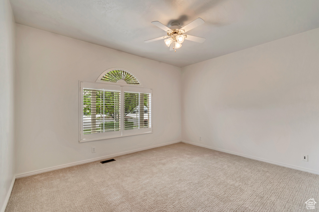 Carpeted empty room with ceiling fan and baseboards