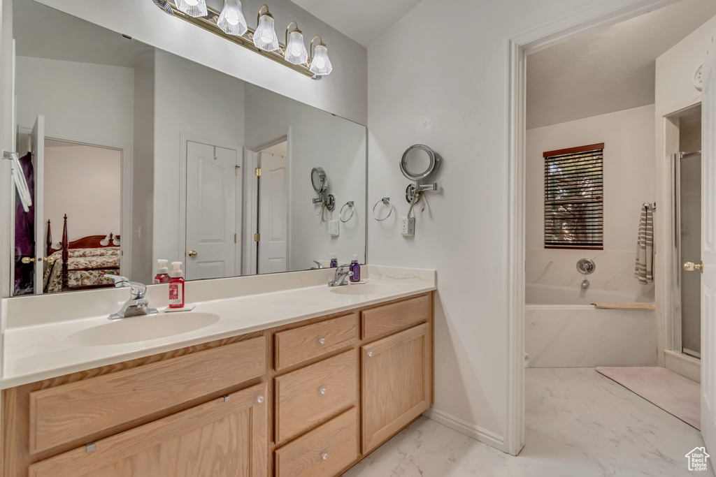 Ensuite bathroom with marble look tile flooring, a bath, double vanity, and a shower stall