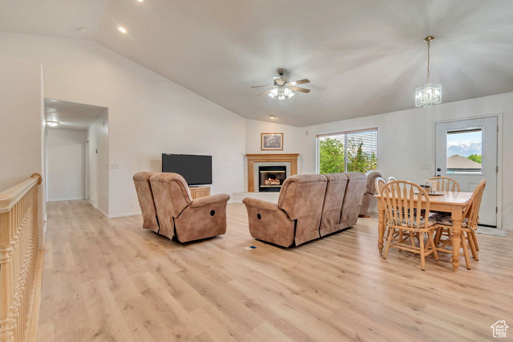 Living room with vaulted ceiling, a ceiling fan, light wood-style floors, recessed lighting, and a glass covered fireplace