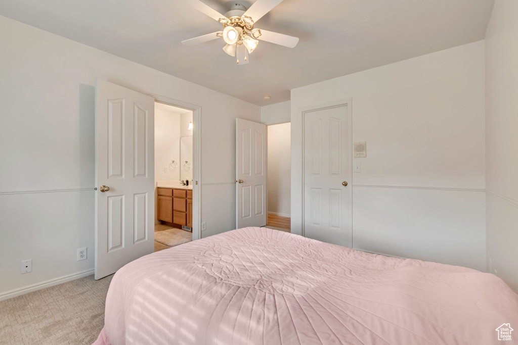 Bedroom featuring baseboards, light colored carpet, ensuite bath, and ceiling fan