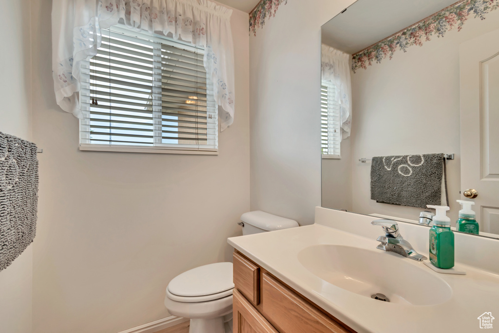 Bathroom featuring plenty of natural light, toilet, and vanity