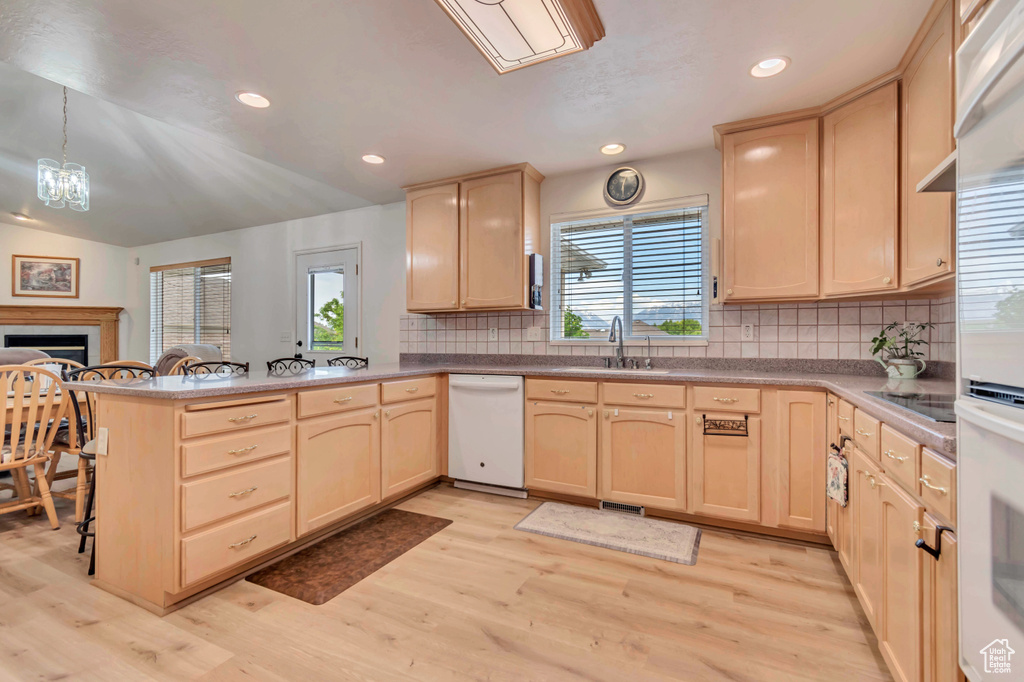 Kitchen with light brown cabinets, a sink, white appliances, healthy amount of natural light, and recessed lighting