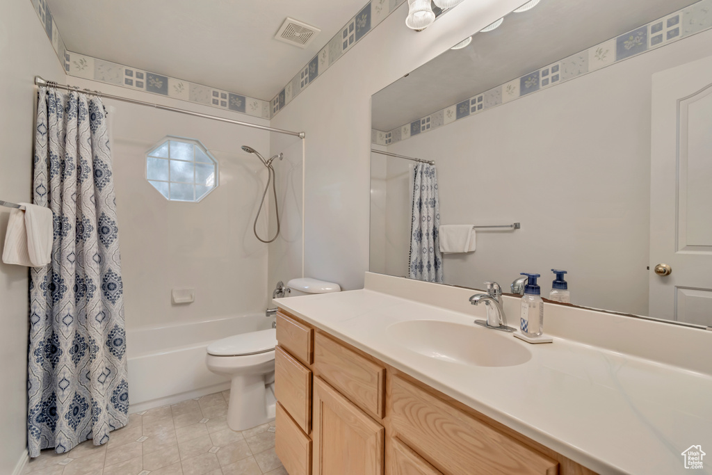 Bathroom featuring vanity, shower / bathtub combination with curtain, toilet, and tile patterned flooring