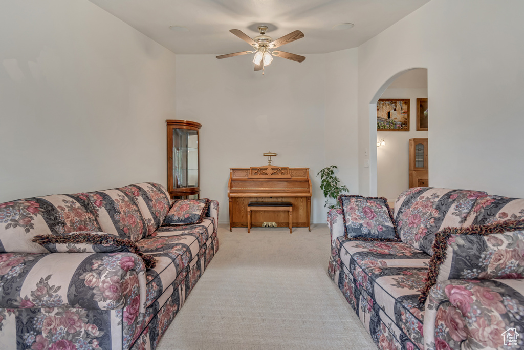 Carpeted living area with arched walkways and ceiling fan