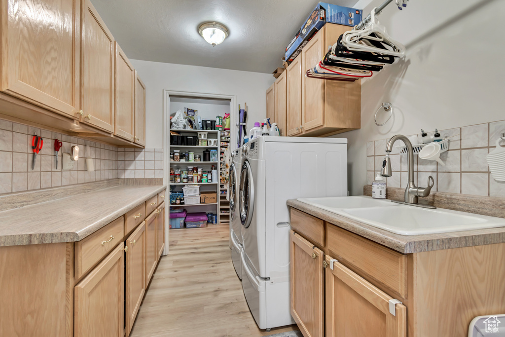 Washroom with cabinet space, washing machine and dryer, and light wood finished floors