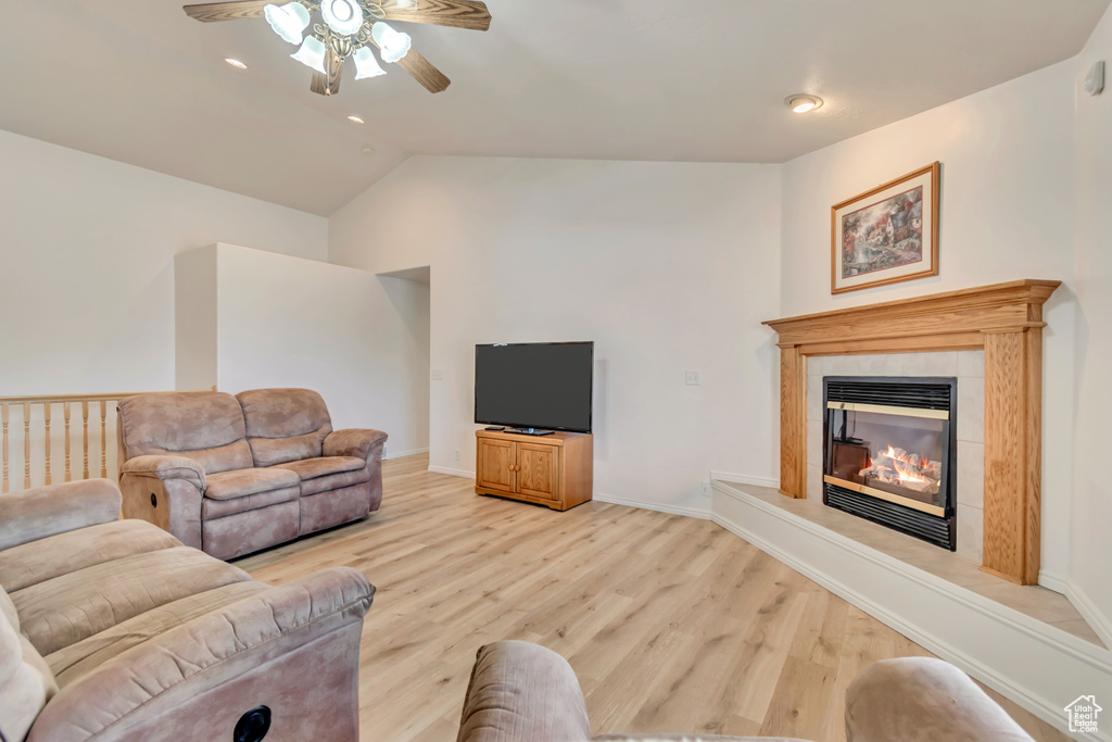 Living room featuring ceiling fan, light wood-style floors, lofted ceiling, a tile fireplace, and recessed lighting