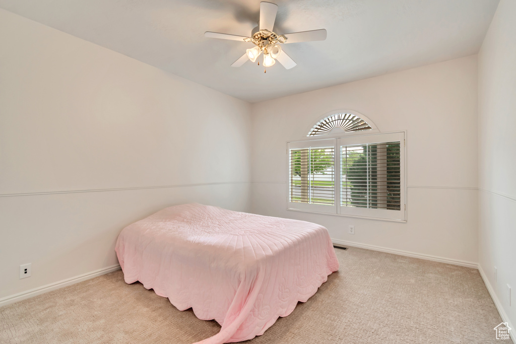 Bedroom featuring light colored carpet, baseboards, and ceiling fan