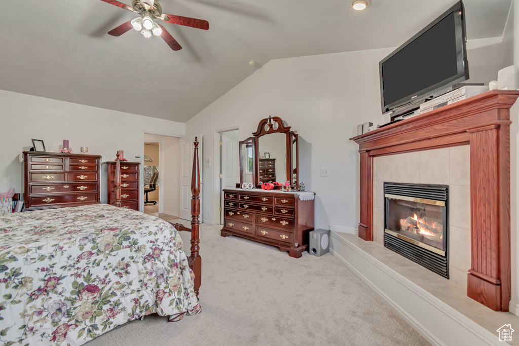 Bedroom with light colored carpet, lofted ceiling, a fireplace, and ceiling fan