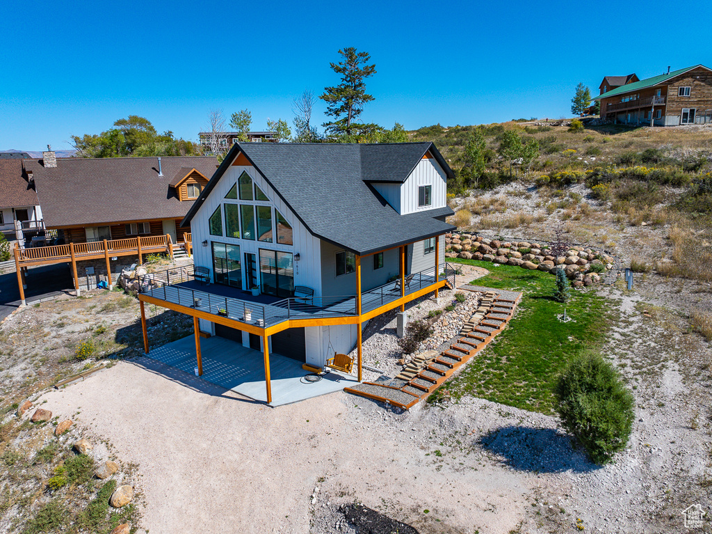 Back of house featuring a wooden deck and a patio area