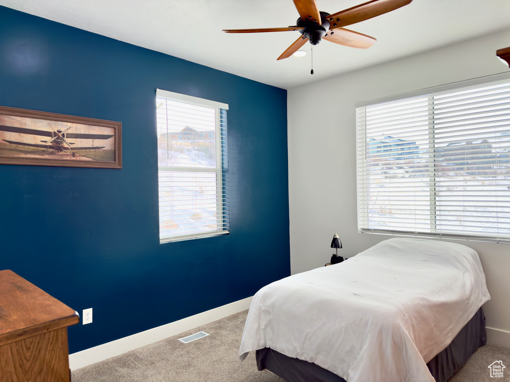 Carpeted bedroom with multiple windows and ceiling fan