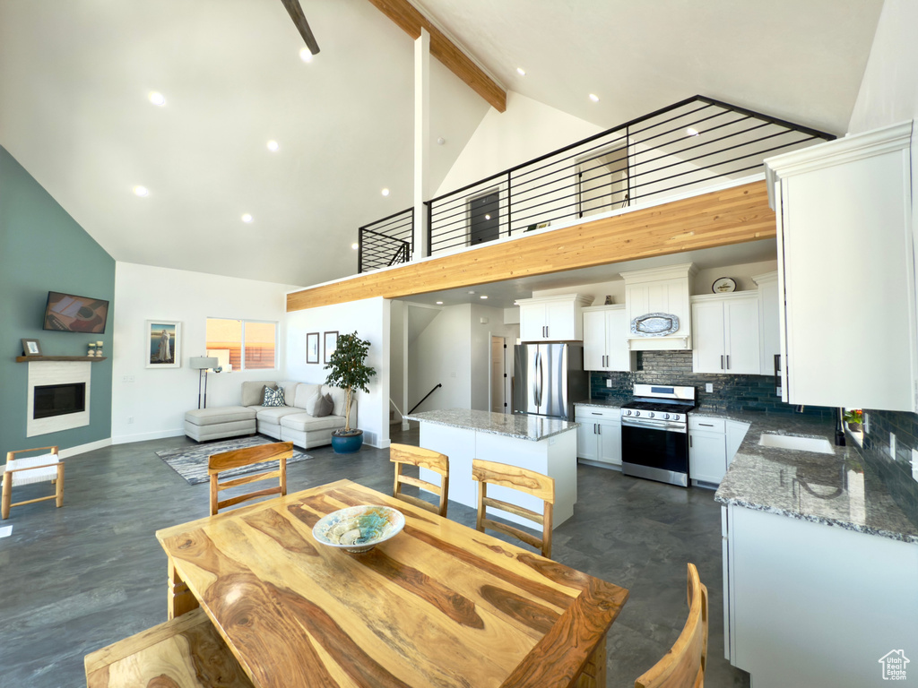 Dining area featuring sink, high vaulted ceiling, and beamed ceiling