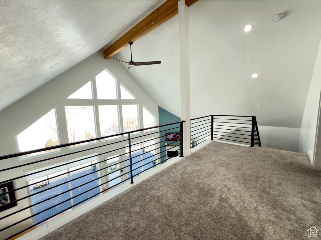 Interior space featuring vaulted ceiling with beams, ceiling fan, and carpet