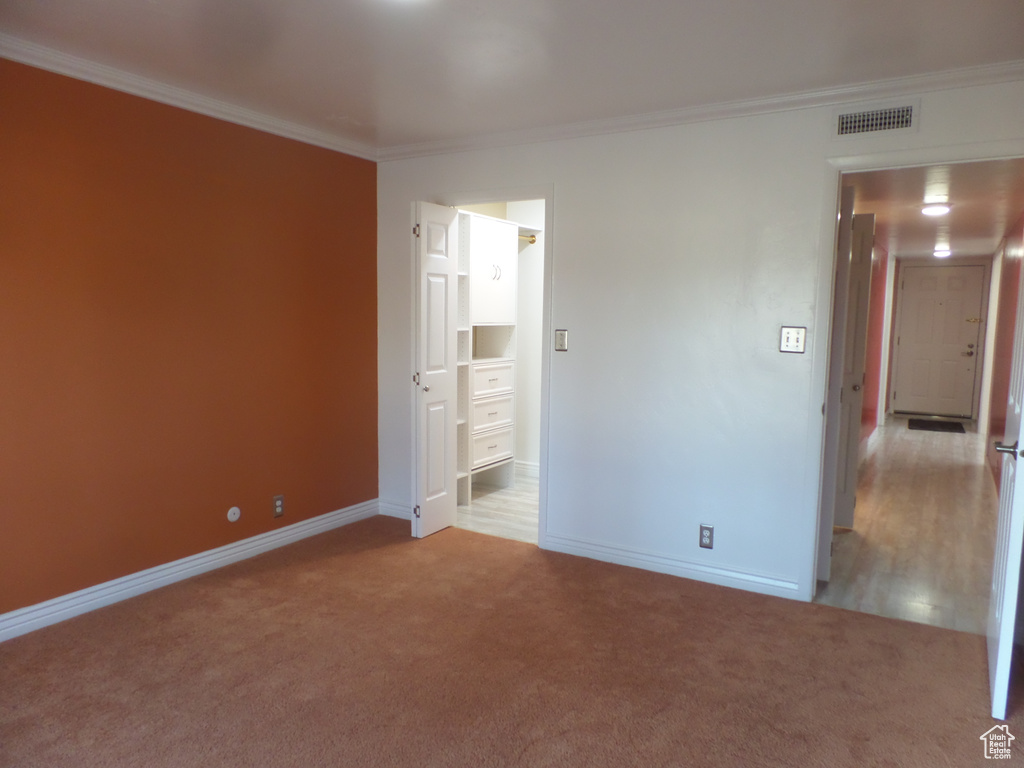 Unfurnished bedroom with ornamental molding, connected bathroom, and light carpet